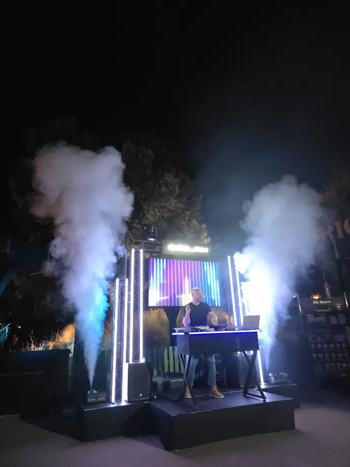 discoteca con dj al aire libre con máquinas de humo